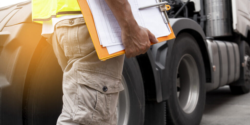 truck driver hand holding clipboard inspecting safety daily check before driving a truck.